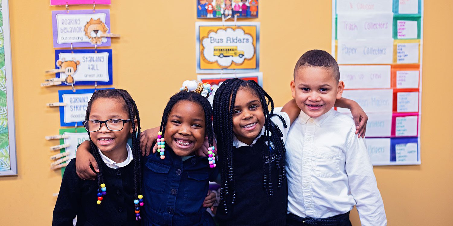 Smiling students standing with arms around each other.